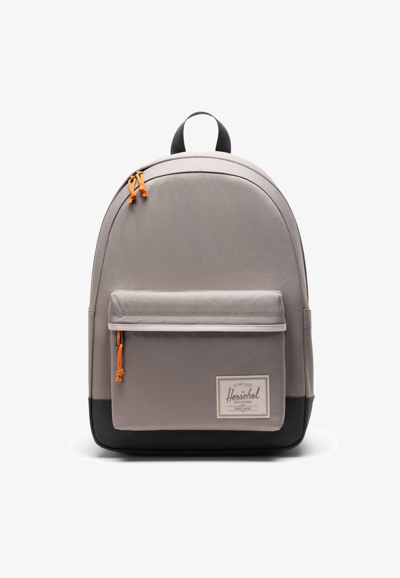 Šedý látkový batoh s křivkovým tvarem, černým dnem, přední kapsou a oranžovými táhly na zip. Obsahuje horní držadlo a nášivku s logem.