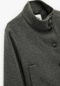 Grauer Wollmantel mit hohem Kragen, ausgestattet mit vier schwarzen Knöpfen und einer Seitentasche. Weiche Textur mit einem strukturierten Design.