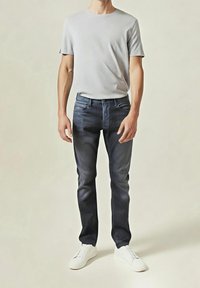 Šedé tričko s kulatým výstřihem, tmavě modré džíny s mírným vyblednutím a bílé tenisky. Neformální střih s minimalistickým designem a bez viditelných vzorů.