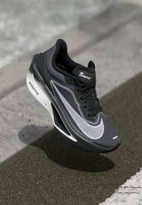Chaussure de course Nike Zoom Fly en noir et gris. Elle dispose d'un dessus en mesh, d'un col rembourré, d'un grand logo swoosh blanc et d'une semelle en mousse légère.