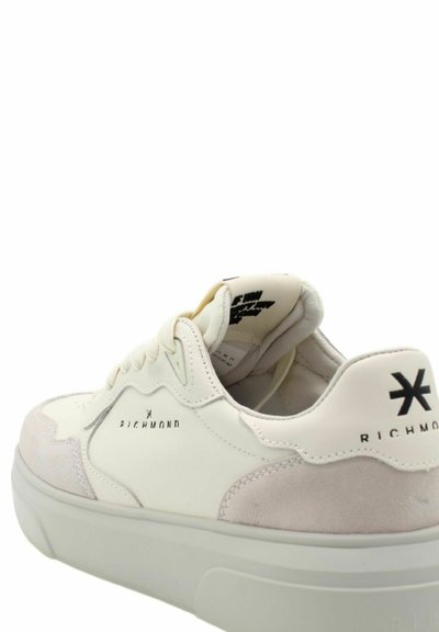 Weißer Sneaker mit Wildleder- und Lederpaneelen. Hat eine abgerundete Zehenpartie, eine dicke Sohle und Branding an der Seite und Ferse. Insgesamt weiche Textur.