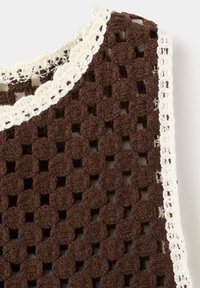 Tissu marron au crochet avec des points circulaires groupés et des carrés ouverts, bordé par une bordure au crochet blanche festonnée.