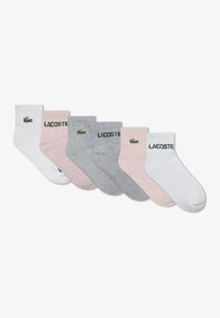 Set of six ankle socks in white, light pink, and gray. Features ribbed cuffs and Lacoste logo in green embroidery on each sock.