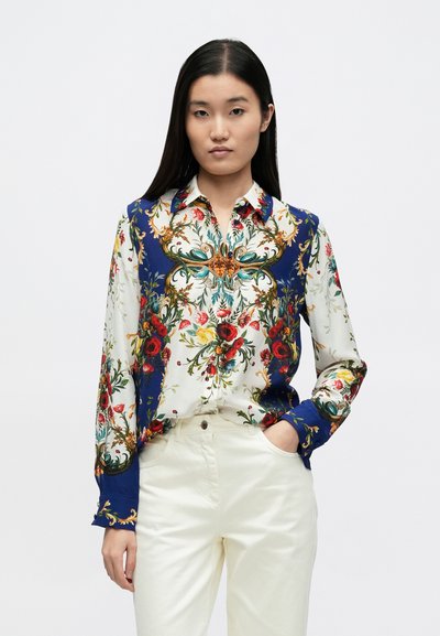 Košeľa s dlhými rukávmi a zapínaním na gombíky, zdobená kvetinovým vzorom na bielo-modrom podklade, s modrými manžetami a prepracovanými zlatými detailmi.