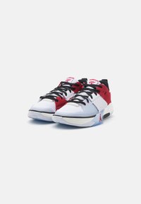 Basketbola apavi ar baltu sieta augšdaļu un sarkanu zamšu akcentu, melnām auklām un caurspīdīgu gumijas zoli. Ievērojams Jumpman logotipa details.