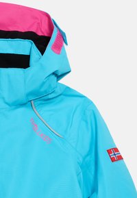 Μπλε παιδικό μπουφάν με ροζ εσωτερική επένδυση, λογότυπο "TROLLKIDS" σε ροζ χρώμα και έναμπαλωμένο έμβλημα της Νορβηγικής σημαίας στο μανίκι.