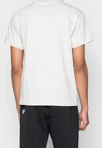 Szara koszulka z krótkim rękawem i okrągłym dekoltem, wykonana z miękkiej bawełny. Widok z tyłu ukazuje gładką teksturę i prosty fason.