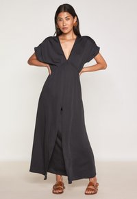 Schwarzes Maxikleid mit tiefem V-Ausschnitt, kurzen Ärmeln, gerafftem Taillenbund und seitlichem Schlitz. Hergestellt aus einem leichten, glatten Stoff.