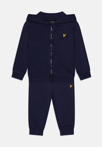 Marineblauwe trainingsset, met een rits hoodie van een zachte stof en een opvallend geel logo, gecombineerd met bijpassende joggingbroek.
