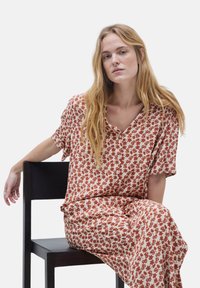 Conjunto de estampado floral en tonos tierra, que presenta un corte relajado con mangas cortas, escote en V y tejido suave y ligero.