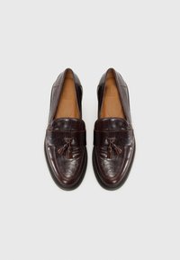 Brown leather loafers with a smooth texture, tassel accent, stitched detail, and a rounded toe design. Brown interior lining.