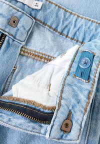 Svijetloplave traperice s patentnim zatvaračem, smešnim šavovima i plavom tkaninom s detaljem gumba. Bijela oznaka vidljiva unutra.