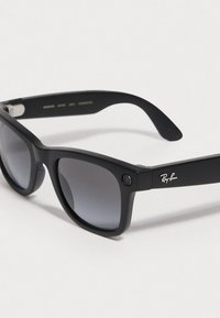 Black sunglasses with a matte finish, rectangular lenses, and gradient tint. Features a silver Ray-Ban logo on the temple and a small camera.