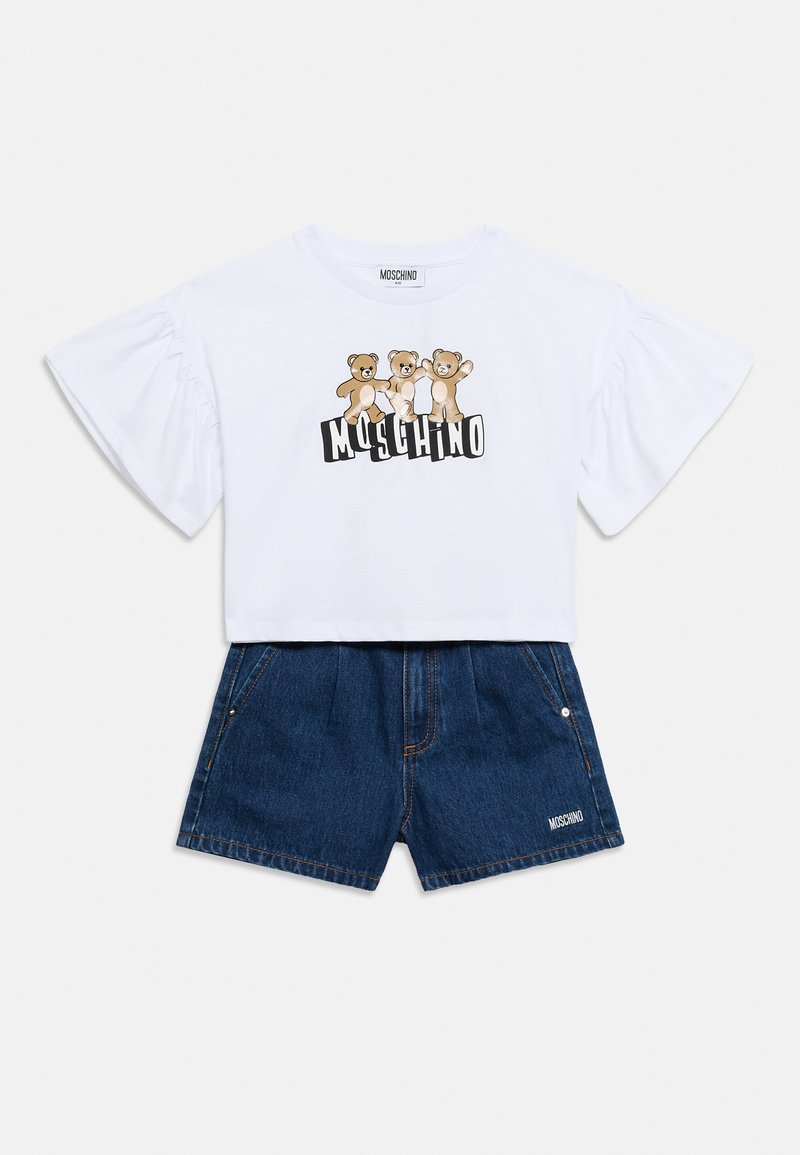 Λευκό κοντό μπλουζάκι με φουσκωτά μανίκια και γραφικό αρκουδάκι, σετ με σκούρα τζιν σορτς που διαθέτουν λογότυπο και πλαϊνές τσέπες.