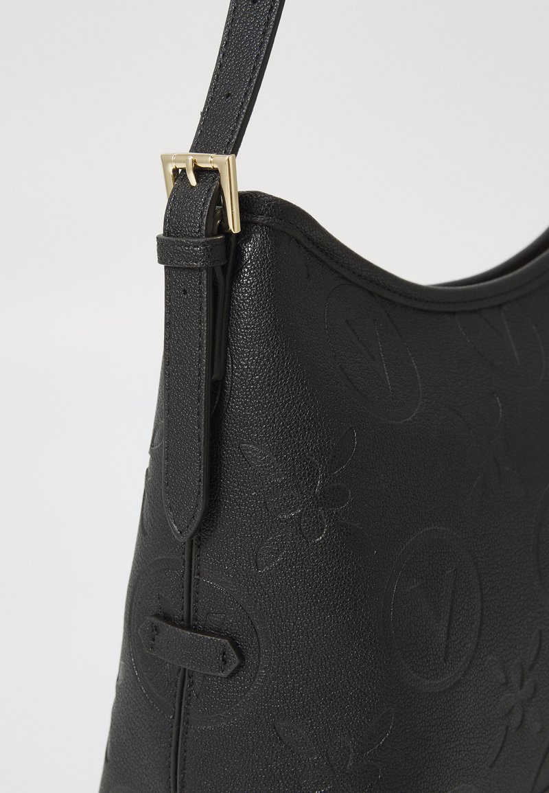 Schwarze Leder-Schultertasche mit geprägtem Blumendesign, verstellbarem Schulterriemen und goldfarbenen Hardware-Details. Glatte Textur und geschwungene Silhouette.