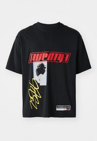 Black cotton t-shirt featuring bold red and yellow graphics, a silhouette design, and a logo patch at the hem. Standard crew neck style.