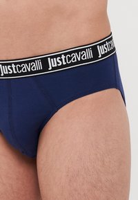 Mornarsko modre bombažne hlačke z črno-bež elastičnim pasom, na katerem je logo "Justcavalli". Gladka tekstura in prilegajoča zasnova.
