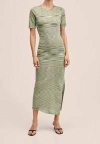 Abito midi a righe verdi realizzato in tessuto elastico, presenta maniche corte e uno spacco laterale, con una texture morbida e una silhouette aderente.