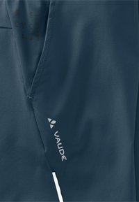 Tamsiai mėlynas lengvas audinys su lygiu paviršiumi. Pritaikytos baltos akcentai ir „VAUDE“ logotipas. Įtrauktas perdirbtų medžiagų žymėjimas.