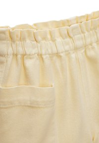 Pantalons en coton jaunes avec une finition texturée, dotés d'une taille élastique et de poches latérales.