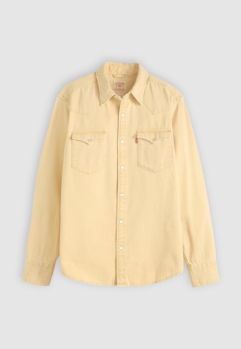 Camisa de mezclilla beige de manga larga con cuello puntiagudo, botones a presión y dos bolsillos en el pecho con tapa y snaps metálicos.