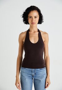 Top de bumbac brun cu gât halter, într-un design ajustat, realizat din material moale, combinat cu blugi ușori cu talie înaltă de culoare albastră.