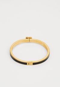 Aukso spalvos apyrankė su juodu emaliu, elegantiško dizaino, minimalistinės formos ir užsegimu.