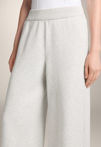 Helle graue, weit geschnittene Sweatpants aus weichem Stoff mit einem gerippten Bund. Verfügt über Seitentaschen und eine strukturierte Oberfläche.