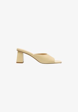 Beige muil met open teen, midhoge blokhak, glad lederen bovenwerk en slip-on ontwerp, van opzij getoond op een witte achtergrond.