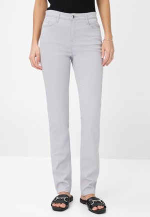 Hellgraue Slim-Fit-Hosen mit mittlerer Taille, Fronttaschen und Reißverschluss. Kombiniert mit schwarzen Slidesandalen mit metallischen Akzenten.