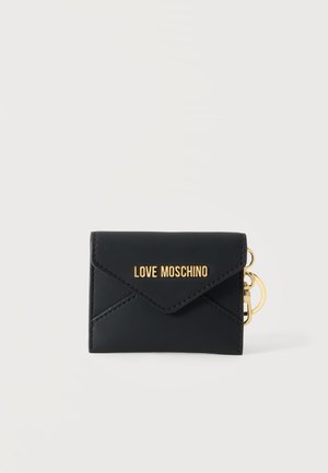 Portefeuille Moschino noir avec logo doré et anneau porte-clés doré sur un fond clair uni.