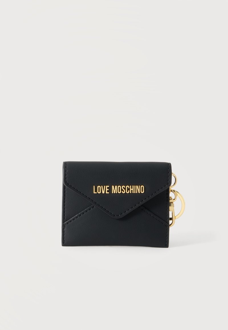 Μαύρο πορτοφόλι Moschino με χρυσό λογότυπο και χρυσό κρίκο μπρελόκ σε ένα απλό φωτεινό φόντο.