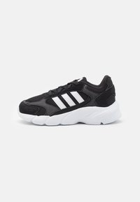 Zapatilla deportiva negra con parte superior de malla, detalles en ante, tres rayas blancas y suela de goma blanca. Diseñada para la comodidad y el soporte.