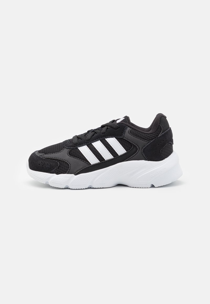 Zapatilla deportiva negra con parte superior de malla, detalles en ante, tres rayas blancas y suela de goma blanca. Diseñada para la comodidad y el soporte.