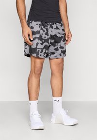 Γκρι αθλητικό σορτς με καμουφλάζ και αντίθετα μοτίβα σε μαύρο και ανοιχτό γκρι. Κατασκευασμένο από αεριζόμενο ύφασμα, διαθέτει ελαστική μέση.