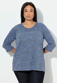 Grijs topje met een blauwe luipaardprint, voorzien van een ronde halslijn en driekwartmouwen. Zachte stof en een ontspannen pasvorm.