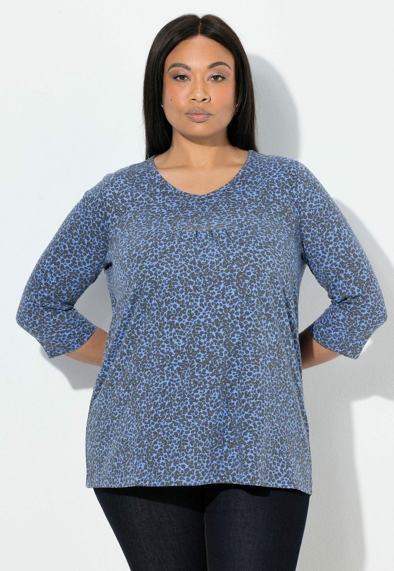 Grijs topje met een blauwe luipaardprint, voorzien van een ronde halslijn en driekwartmouwen. Zachte stof en een ontspannen pasvorm.