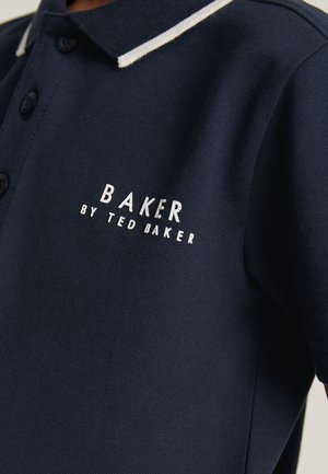 Polo azul marino con ribete blanco en el cuello y logo blanco "Baker by Ted Baker" bordado en el pecho.