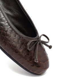Bruine leren balletschoenen met een gestructureerd, schubachtig patroon, ronde neus en decoratieve strikaccent. Zachte binnenvoering en platte zool.