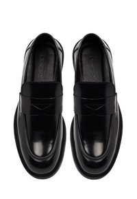 Zwarte leren loafers met een glanzende afwerking, voorzien van een ronde neus en een decoratieve band over de bovenkant. Glad oppervlak en robuuste zool.