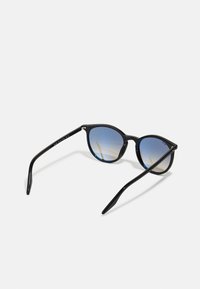 Ochelari de soare negri cu un design rotund, în stil cat-eye. Lentile irizate cu un gradient albastru. Temele subțiri negre cu un detaliu subtil de branding.