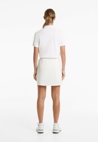 White polo shirt and a white skirt, both with a smooth texture. The outfit features a subtle elastic waistband and classic design.