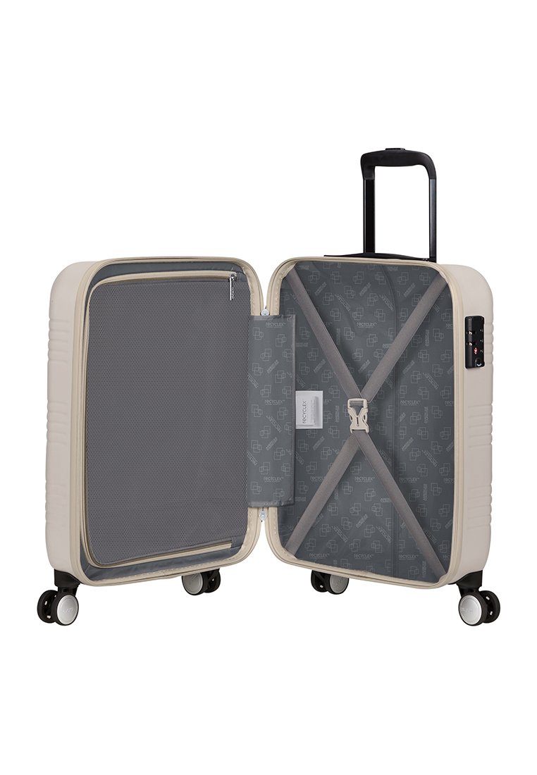 Valise rigide, couleur crème, avec poche en maille intérieure, doublure à motif gris, sangles croisées et poignée rétractable sur le dessus. Quatre roues.