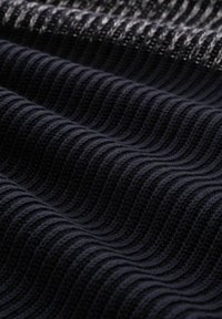 Schwarzer, gestrickter Stoff mit einem strukturierten Wellenmuster. Das Material hat ein weiches, leicht elastisches Aussehen und betont Tiefe und Dimension.