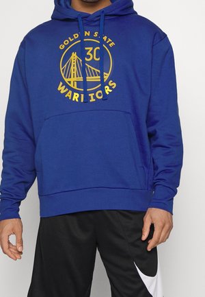 Homme portant un sweat à capuche bleu Golden State Warriors avec cordons et un short noir Nike avec logo swoosh blanc.