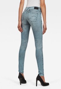 Úzké džíny ve světle modrém denimovém provedení. Vysoký pas s dvěma zadními kapsami. Tkanina má texturovaný povrch se subtilními detaily vyblednutí.