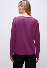 Pull en maille violet avec un col rond, des manches longues et un ourlet côtelé. Texture lisse mettant en valeur une couleur unie sans motifs.