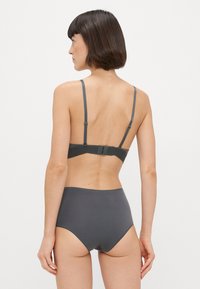 Szürke fehérnemű szett, amely puha textúrájú melltartóból áll, állítható vállpántokkal, és egy magasan vitt bugyiból, mindkettő sima felülettel rendelkezik.