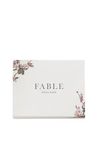 Białe pudełko z kwiatowymi akcentami na narożnikach i napisem "FABLE ENGLAND" w eleganckiej pisanej czcionce na środku.