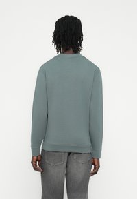 Γκρι φούτερ με μακριά μανίκια, στρογγυλή λαιμόκοψη και ριμπ μανσέτες. Κατασκευασμένο από μαλακό υλικό, διαθέτει υφή και άνετη εφαρμογή.